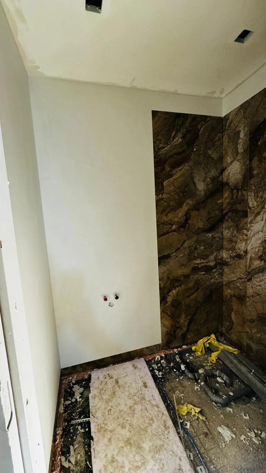 Gestucte wand naast tegelwerk in marmerlook.